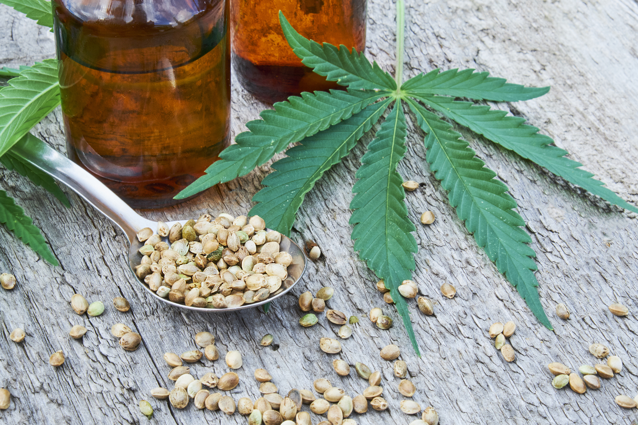 hemp leaves on wooden background, seeds, cannabis oil extracts in jars